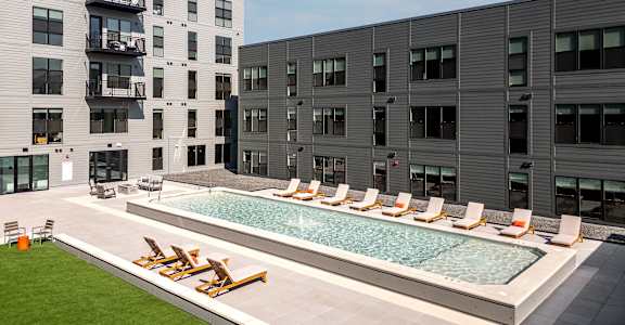 a swimming pool in the middle of two apartment buildings at The Edwin on Grand Apartments, Missouri