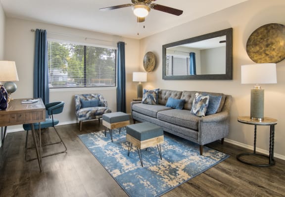 Comfortable living room with grey couch and ottomans in an apartment for rent at Forest Ridge apartments for rent in Macon, GA