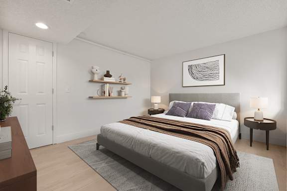 A bedroom with a large bed and a small table with a plant on it. at AVIA Lofts on Parkway, Vancouver, WA 98662