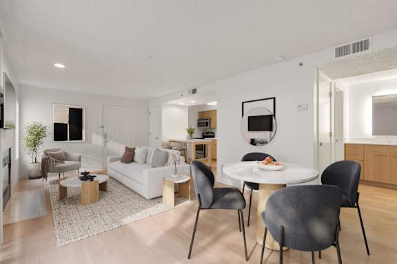 A modern living room with a white couch, a coffee table, and a dining table with chairs. at AVIA Lofts on Parkway, Vancouver Washington