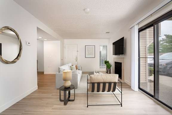 A modern living room with a white sofa, a black and white striped chair, and a round mirror on the wall.