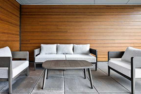 A modern living room with a wooden wall and a grey sofa.