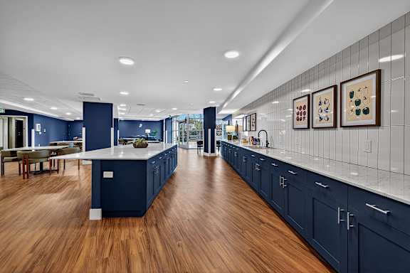 A modern kitchen with dark blue cabinets and a long white island.