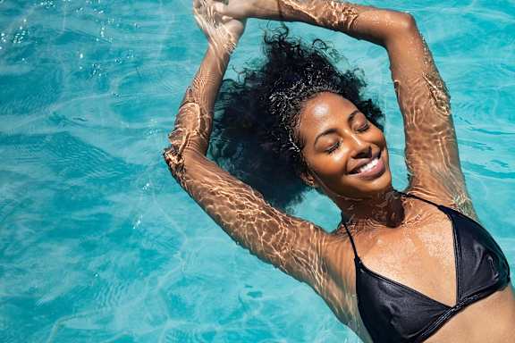 A woman in a black bikini is floating in a pool.