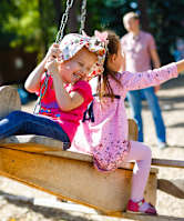 Two children playing on a swing set.