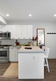 A modern kitchen with white cabinets and stainless steel appliances.