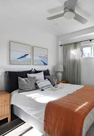 A bedroom with a bed, nightstand, and a painting on the wall.