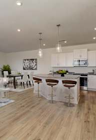 A modern kitchen with white cabinets and a wooden floor.