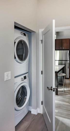 A laundry room with a washer and dryer, a bathroom with a sink and mirror, and a doorway leading to a kitchen.