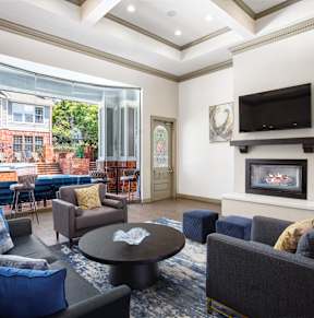 A spacious living room with a grey sofa and a blue rug.