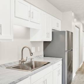 a white kitchen with a stainless steel refrigerator and sink