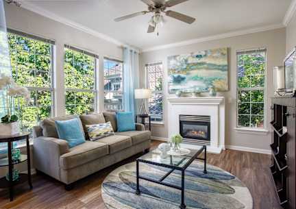 A living room with a grey couch and a glass coffee table.