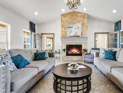 A clubroom with a fireplace and two grey couches.