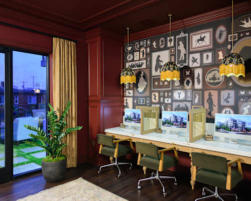 A room with a long table and chairs with a wall of pictures behind it.