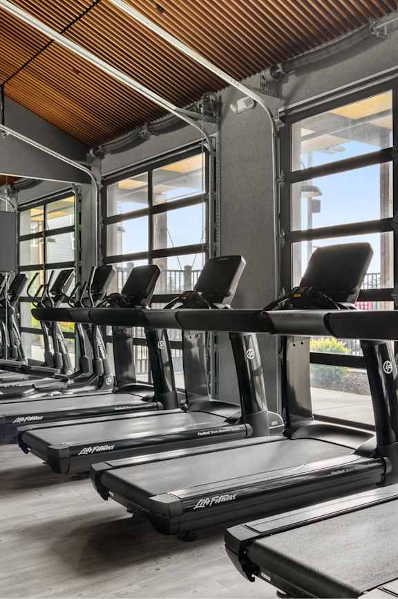 A gym with treadmills and a wooden floor.