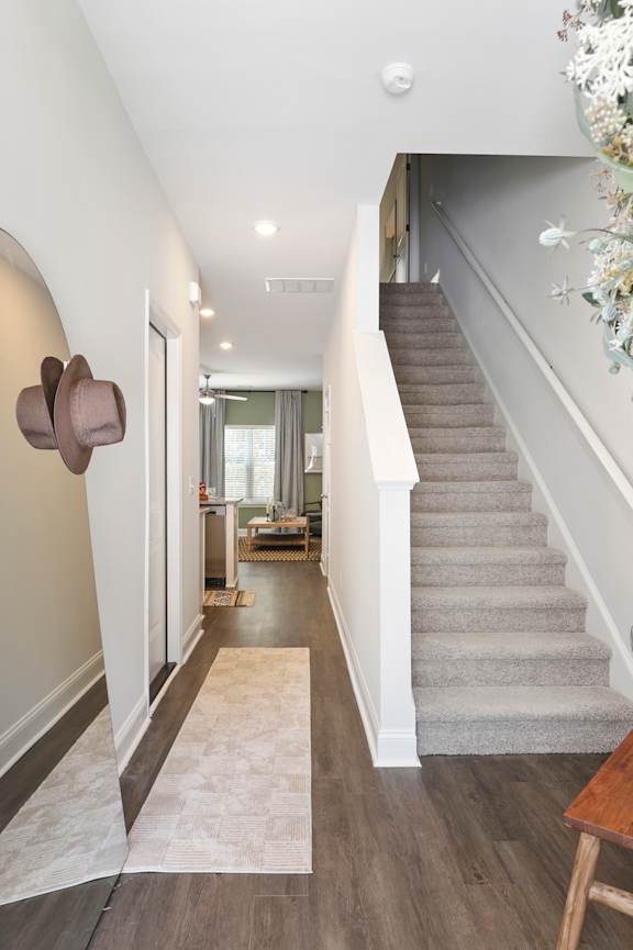 A hallway with a staircase and a mirror on the wall.