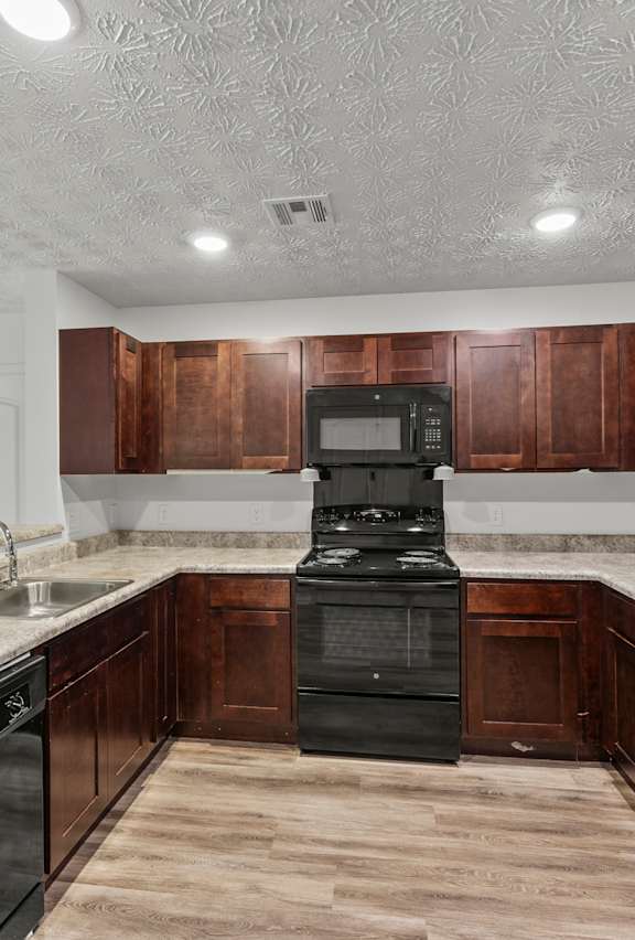 A kitchen with black appliances and wooden cabinets.