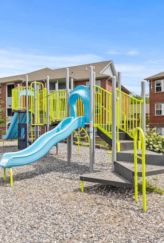 A playground with a blue slide and yellow railing.