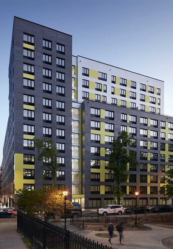 A modern building with a glass facade is illuminated from within, casting a warm glow on the exterior.