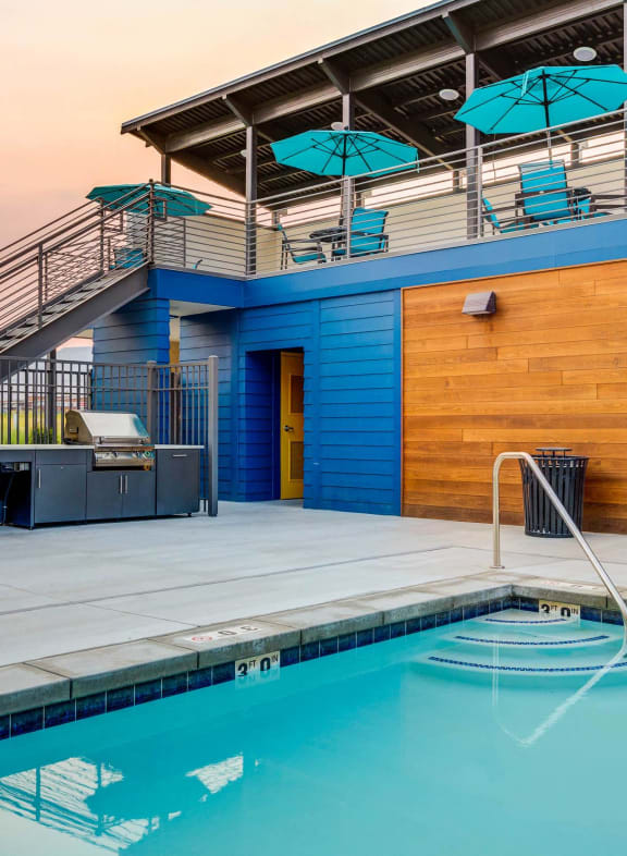 the pool and poolside deck of a blue building with a swimming pool and stairs