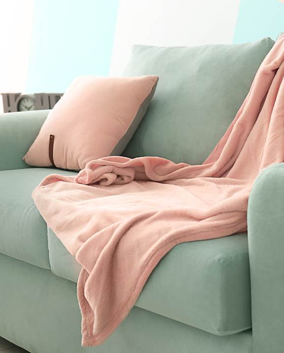 A pink blanket is draped over a green couch.