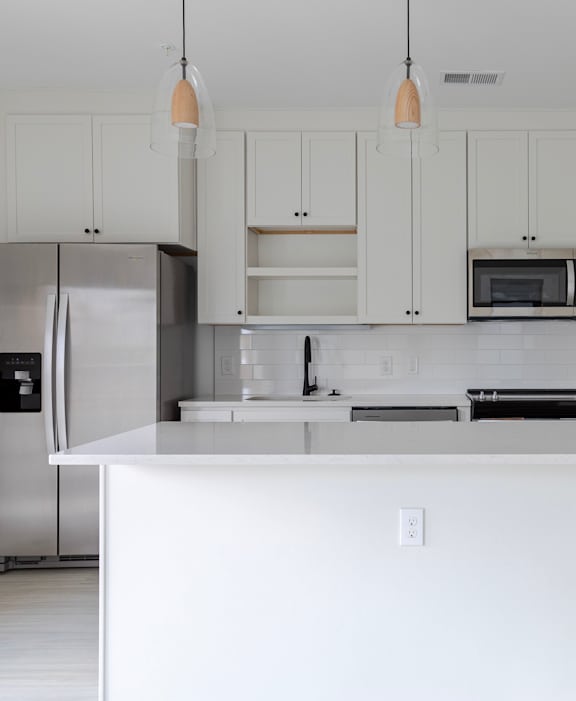 A white kitchen with a refrigerator, microwave, and cabinets.