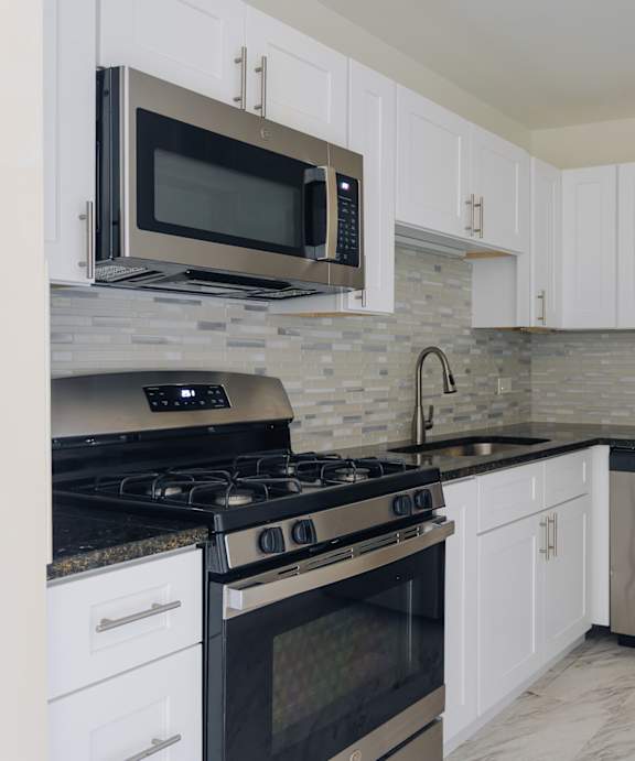 A kitchen with a stove, oven, refrigerator, and microwave.