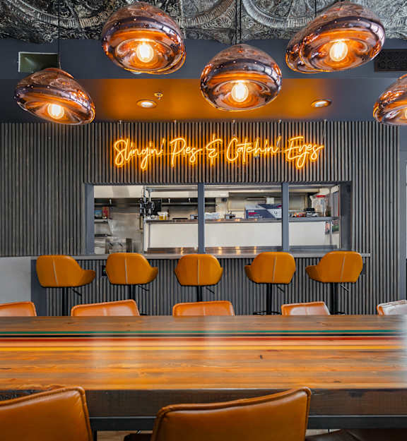 Three copper cups with garnishes sit on a bar counter in front of a shelf of bottles.