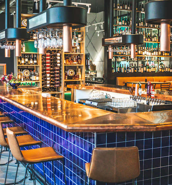 A bar with a blue tile backsplash and a wooden counter.