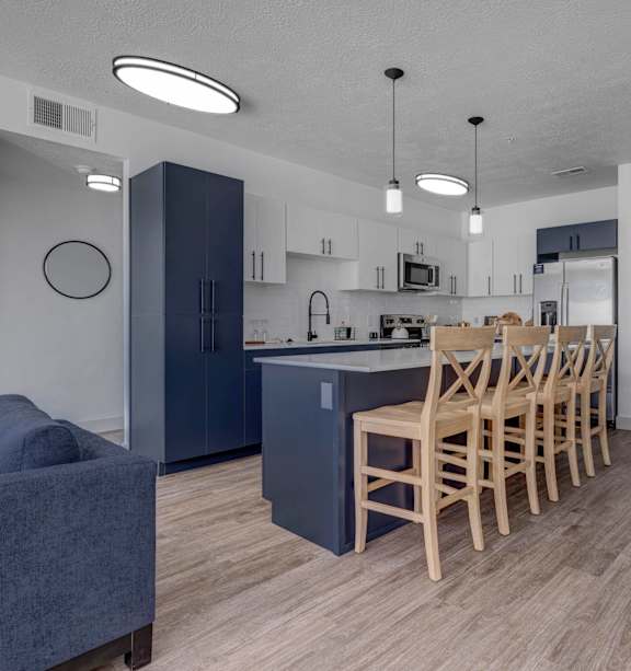 A kitchen with a blue couch and wooden chairs.