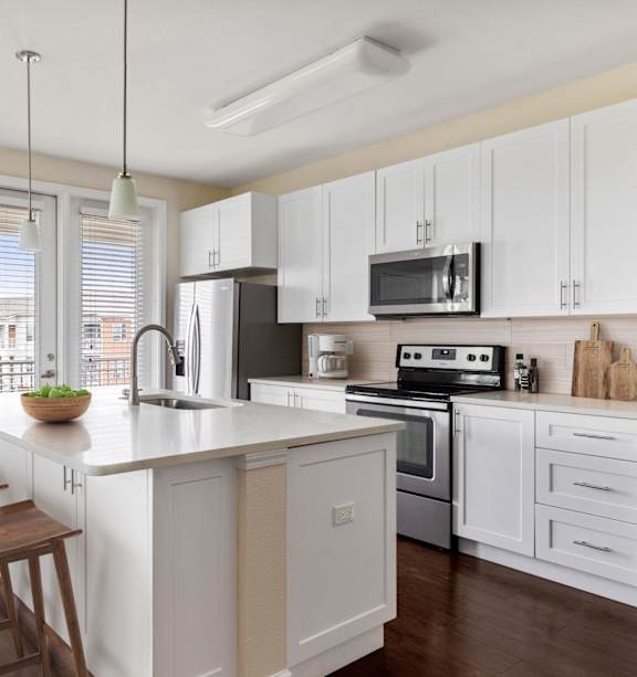 A kitchen with white cabinets and a wooden island.