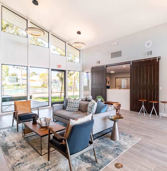 A conference room with a table surrounded by chairs and a clock on the wall at Chaparral Apartments , California 93551