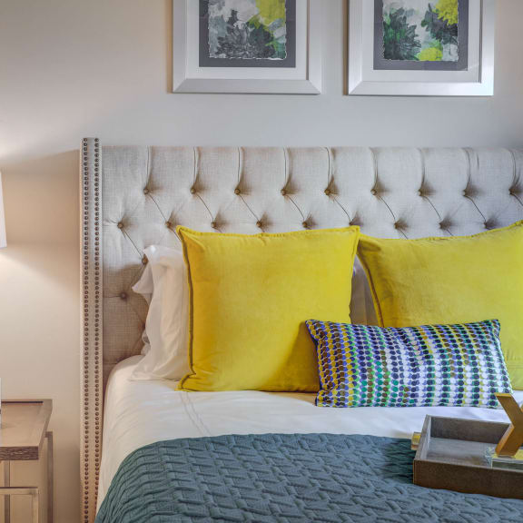a bedroom with a bed and yellow pillows and a nightstand with a lamp