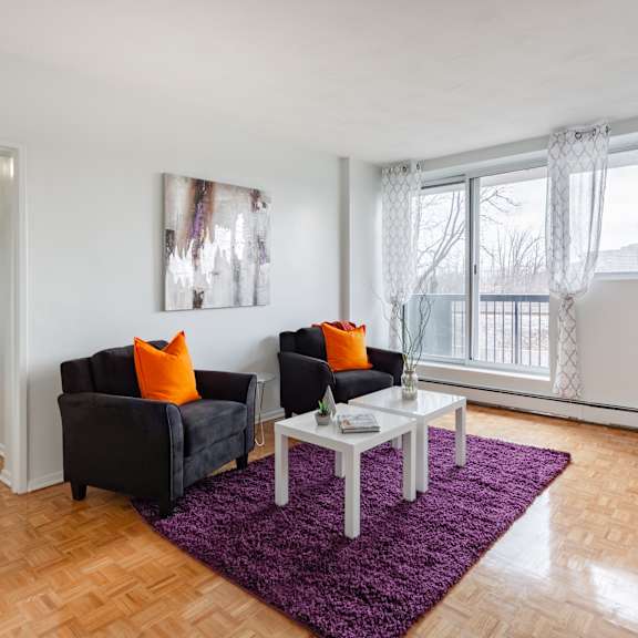 A living room with a black couch, a white coffee table, and a purple rug.