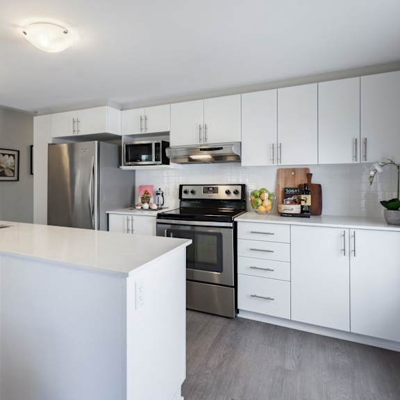 A modern kitchen with white cabinets and stainless steel appliances.