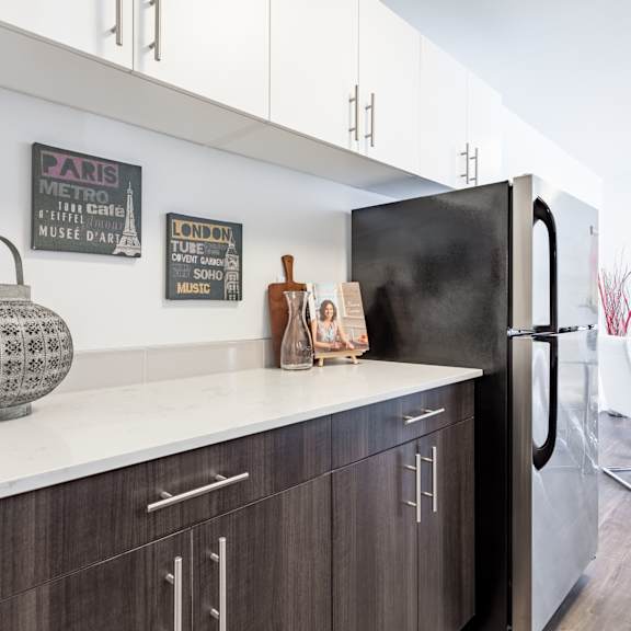 A kitchen with a black refrigerator and wooden cabinets.