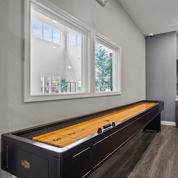 A pool table is in the middle of a room with a window.