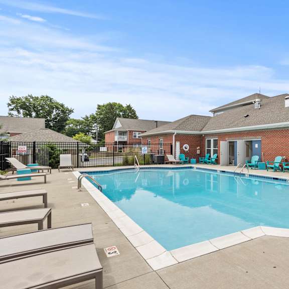 A large outdoor swimming pool with lounge chairs and a building in the background.