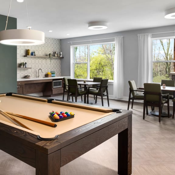a pool table in a living room with a dining room and a kitchen