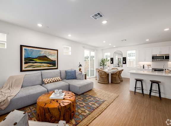 A modern living room with a kitchen in the background.