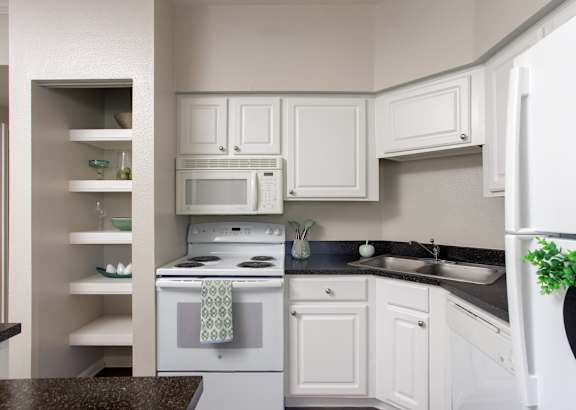 A kitchen with white cabinets and a black countertop.