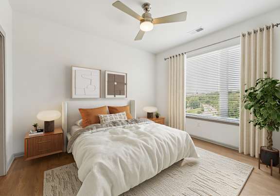 A bedroom with a large bed, a ceiling fan, and a potted plant.