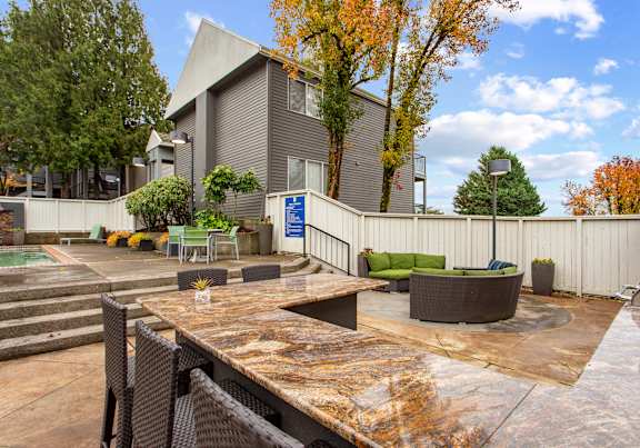 A table with a plant on it sits in front of a pool.