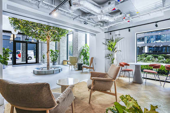 a living room with chairs and tables and a tree in the middle