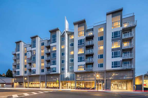 A large, modern apartment building with multiple balconies and a flag on top.