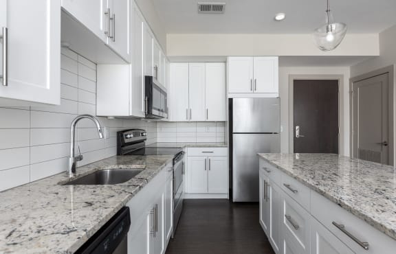 A kitchen with white cabinets and granite countertops. at Hibernia Apartments, St Louis, Missouri