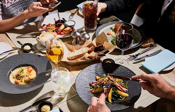 A group of people are dining at a restaurant with plates of food in front of them.