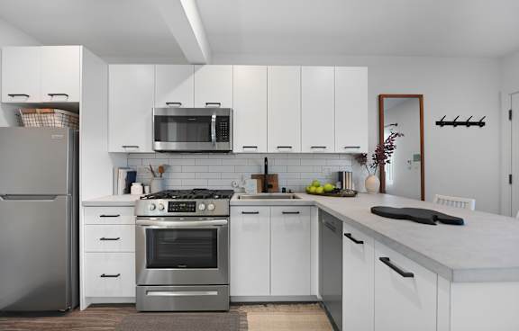A modern kitchen with white cabinets and stainless steel appliances.