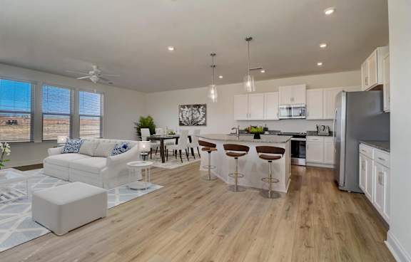 A modern kitchen with white cabinets and a wooden floor.