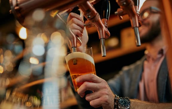 a man pouring a beer into a glass in a bar
